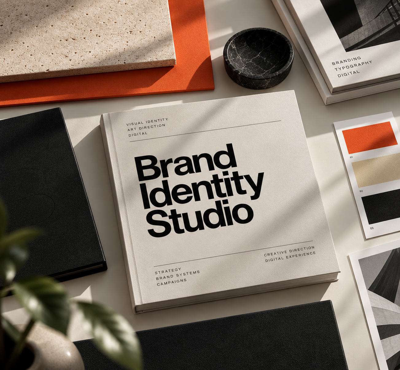 Brand identity book on a studio table with colour swatches, stone samples and black folios in soft sunlight
