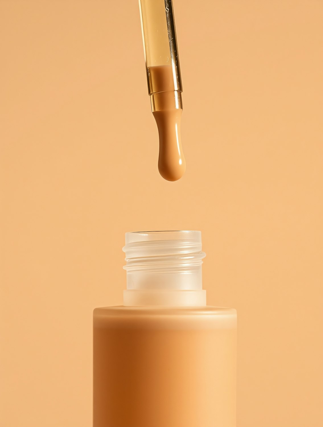 Close-up of an Aura dropper bottle on a warm beige surface